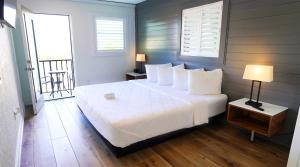 a bedroom with a large white bed and a balcony at Devon Shores in Clearwater Beach