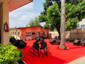un gruppo di sedie su un tappeto rosso con un edificio di Classicus Inn & Apartments a Ibadan