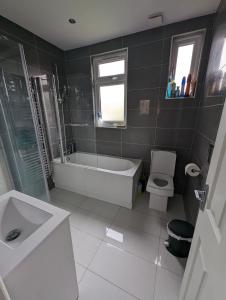 uma casa de banho com uma banheira, um WC e um lavatório. em Luxury Hotel Rooms em Palmers Green