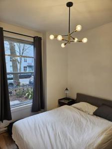 a bedroom with a bed and a window with a chandelier at Chic Modern Apt in The Plateau in Montreal