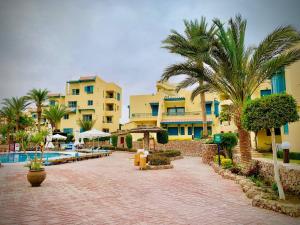 a resort with a pool and palm trees and buildings at Eagles Downtown Resort in Hurghada