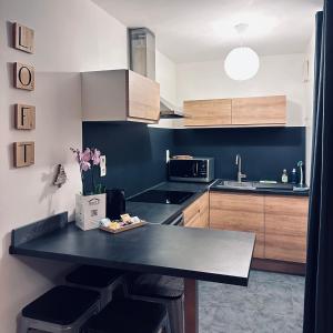 een keuken met een zwart aanrecht en houten kasten bij Beautiful apartment * parking* Disneyland 10 min in Montévrain