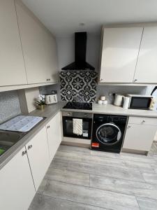a kitchen with white cabinets and a washer at Home from home The Orchid with Hot tub in Colnbrook