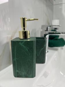 a green soap dispenser sitting on a bathroom counter at Home from home The Orchid with Hot tub in Colnbrook