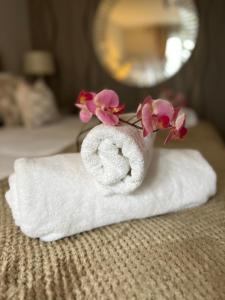 a towel with flowers on top of it on a bed at Home from home The Orchid with Hot tub in Colnbrook