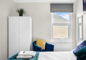 a bedroom with a bed and a blue chair and a window at Uksas Two bed Flat Free Parking in London