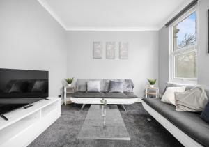 a white living room with a couch and a tv at Uksas Two bed Flat Free Parking in London