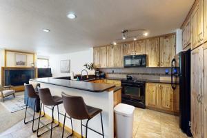 a kitchen with wooden cabinets and a black refrigerator at Skiers Paradise in Keystone