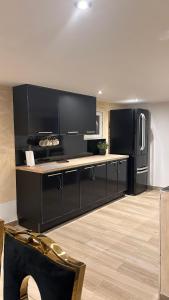 a kitchen with black cabinets and a refrigerator at 1001 nuits F in Fénay