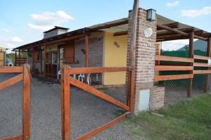 un edificio de ladrillo con una puerta y una valla en Cabañas en La Gloria en Villa Elisa