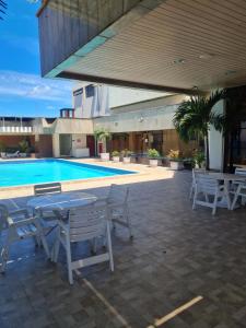 a patio with a table and chairs next to a swimming pool at Flat Praia da Costa in Vila Velha