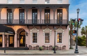 Mills House Charleston, Curio Collection by Hilton في تشارلستون: مبنى وردي مع شرفة على شارع