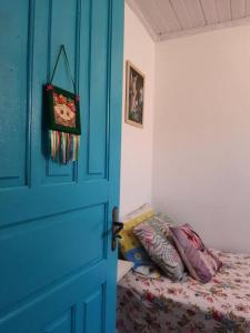 um quarto com uma porta azul e uma cama com almofadas em Casa da Bru pertinho da praia e da lagoa em Rio das Ostras