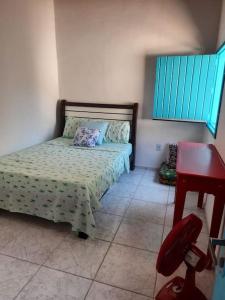 um quarto com uma cama e uma secretária vermelha em Casa da Bru pertinho da praia e da lagoa em Rio das Ostras