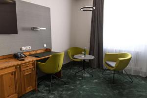 Habitación con escritorio, 2 sillas y mesa. en Hotel Gut Matheshof, BW Signature Collection, en Rieden