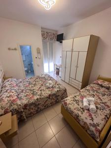 una camera d'albergo con due letti e un bagno di Hotel Ilde a Rimini
