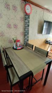 mesa de comedor con sillas y reloj en la pared en 3Js Place 30-mins from Tagaytay, en General Trias