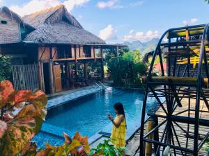 a woman in a yellow dress standing next to a pool at Pù Luông Happy Home in Lũng Tiềm