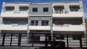 a white building with a fence in front of it at Departamento nuevo en San Bernardo in San Bernardo