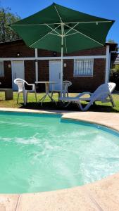 einen Tisch mit Stühlen und einen Sonnenschirm neben einem Pool in der Unterkunft La Algarroba in Alta Gracia
