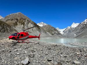 a red helicopter parked next to a mountain lake at Drifting Sands Beachfront Retreat in Hokitika