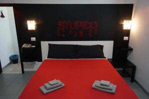 a bedroom with a red bed with two towels on it at Stupido Hotel Rimini in Rimini