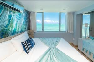 a bedroom with a large white bed with a view of the ocean at Enchanted Honeymoon Isla Verde Beachfront in San Juan