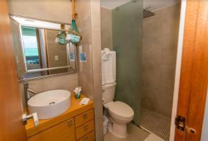 a bathroom with a toilet and a sink and a mirror at Enchanted Honeymoon Isla Verde Beachfront in San Juan