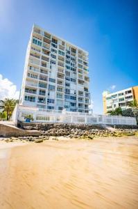 ein hohes Gebäude neben einem Strand mit einem Gebäude in der Unterkunft Enchanted Honeymoon Isla Verde Beachfront in San Juan