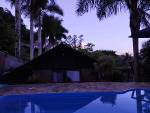 a house with a swimming pool and palm trees at Casa da Lagoa - Gasthaus Pomerode in Pomerode