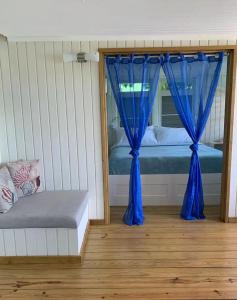 um quarto com uma cama com cortinas azuis e um banco em Emma's by the Sea em Culebra