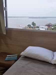 a bed in a room with a view of the ocean at Vista Guaíba e Cais Embarcadero in Porto Alegre