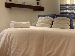 uma cama com lençóis brancos e almofadas azuis em Villa Coyoacan em Cidade do México