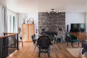 a living room with a table and a stone fireplace at Magnifique chalet au bord du lac avec Spa in Saint-Alexis-des-Monts