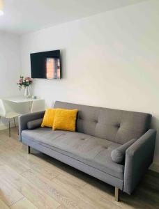 un divano grigio con cuscino giallo in soggiorno di Roomello luxury City Studios a Peterborough