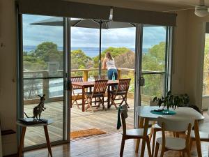 Sunrise on Falie Seaview Eco Accommodation في American River: امرأة تقف على شرفة منزل