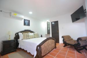 sypialnia z łóżkiem, krzesłem i telewizorem w obiekcie CASA KATALINA w mieście Cartagena de Indias