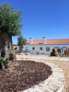 a house with a tree and a walkway at Casas de Miróbriga in Santiago do Cacém