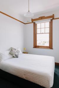 uma cama branca num quarto com uma janela em Shipwrights Arms Hotel em Hobart