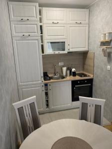 uma cozinha com armários brancos, uma mesa e um lavatório em Adriatic apartman em Budva