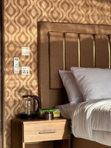 łóżko z drewnianą szafką nocną obok łóżka z czajnikiem do herbaty w obiekcie Wadi Rum Golden Valley w mieście Wadi Rum