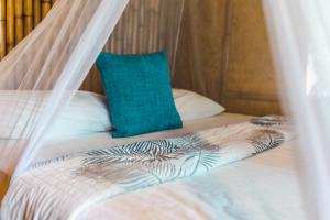 a bed with a mosquito net and a blue pillow at Bamboo Bay Island Resort in Srithanu