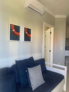 a living room with a blue couch and two pictures at Boulevard Riviera Flat in Riviera de São Lourenço