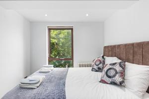Elegant Living in Kingston: Two Bedroom Apartment في كينجستون أبون تيمز: غرفة نوم بسرير ومخدات ونافذة