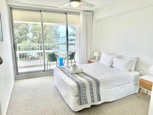 Dormitorio blanco con cama y ventana grande en Hillhaven Holiday Apartments, en Gold Coast