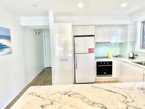 cocina con armarios blancos y nevera en Hillhaven Holiday Apartments, en Gold Coast