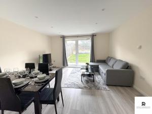 a living room with a table and a couch at Newly Launched Two Bedroom House By Den Accommodation Short Lets & Serviced Accommodation With Garden in London