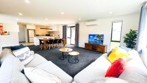 un salon avec un canapé blanc et une table dans l'établissement Brand New House with 5 bedroom and 3 full bathroom, à Rotorua