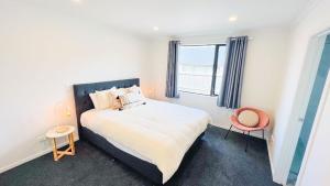 une chambre avec un grand lit et une fenêtre dans l'établissement Brand New House with 5 bedroom and 3 full bathroom, à Rotorua