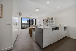 a white kitchen with a refrigerator and a table at Cosy 1-Bed With Balcony Pool & Leisure Area in Lyons
